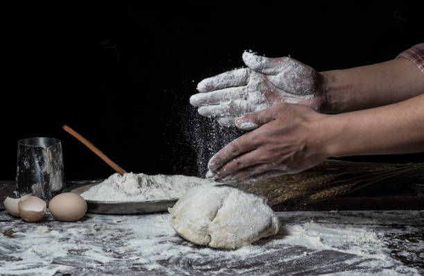 istock Man preparing bread dough on wooden table in a bakery close up 942558894