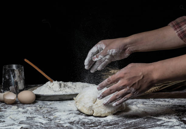 istock Man preparing bread dough on wooden table in a bakery close up 942559008