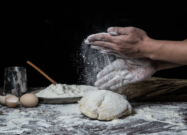 istock Man preparing bread dough on wooden table in a bakery close up 942559334