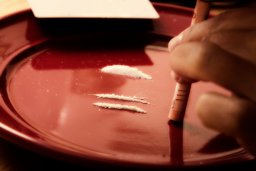 Snorting cocaine drugs off a red plate
