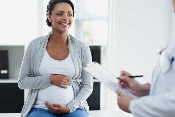 I'm just going to ask a few questions Shot of an confident female doctor consulting with a pregnant patient at a hospital during the day maternity ward stock pictures, royalty-free photos & images