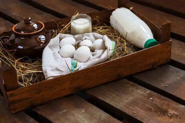 Chicken eggs and rural milk in wooden to box on a wooden table. Rustic style