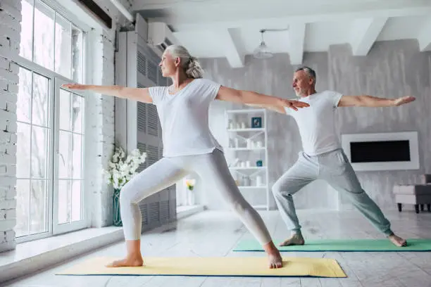 Senior couple is doing fitness training at home. Doing yoga together. Healthy lifestyle concept.