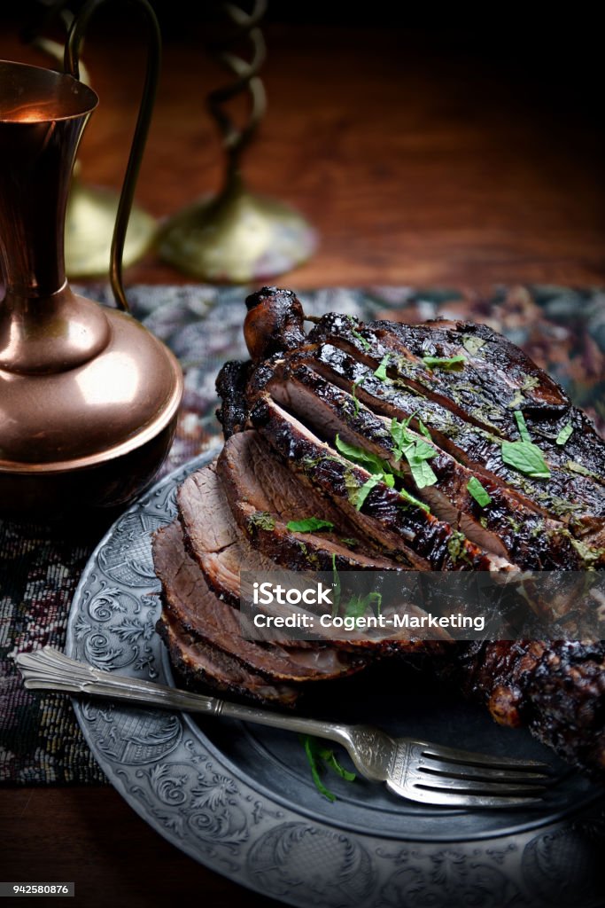 Roast Leg of Lamb III Home roasted whole leg of New Zealand lamb, slow roasted with rosemary, mint, red wine, shallots, roasted potatoes and caramalized carrots. Accommodation for copy space. Food Stock Photo