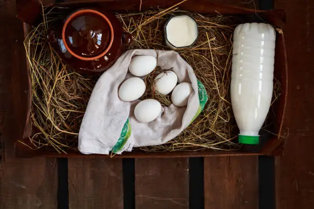 Chicken eggs and rural milk in wooden to box on a wooden table. Rustic style. Top view