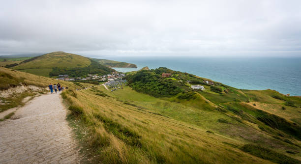 High view across English coastal landscape and Lulworth Cove, Dorset Jurassic Coast path at high altitude descending down to Lulworth Cove below, with amazing views across the green Dorset landscape jurassic coast world heritage site stock pictures, royalty-free photos & images