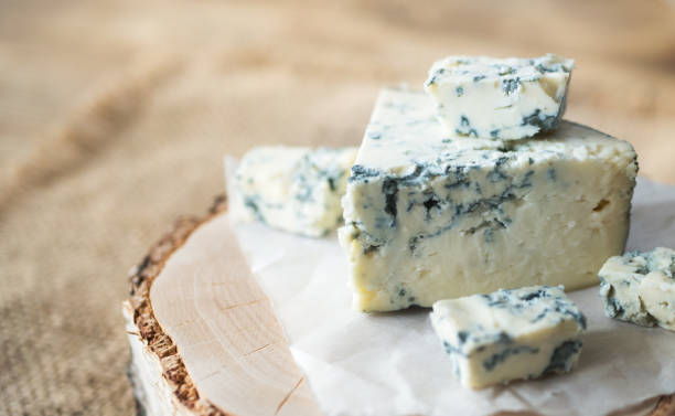 käsescheiben auf einem holzbrett, selektiven fokus dorblu. stücke von lecker blauschimmelkäse - blauschimmelkäse stock-fotos und bilder