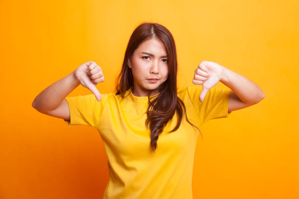 istock Unhappy Asian girl show thumbs down with both hands. 942585522