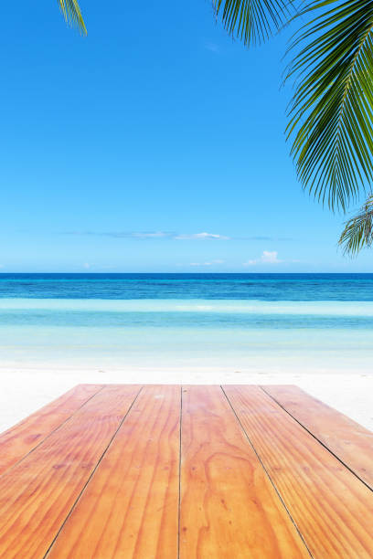 istock Empty wooden table beside tropical paradise beach 942602802
