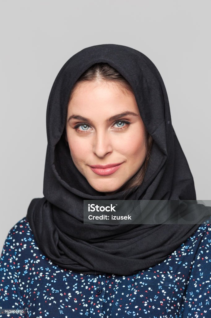 Portrait of confident young muslim woman Portrait of cheerful young muslim woman. Businesswoman in hijab looking at camera against grey background. 20-29 Years Stock Photo