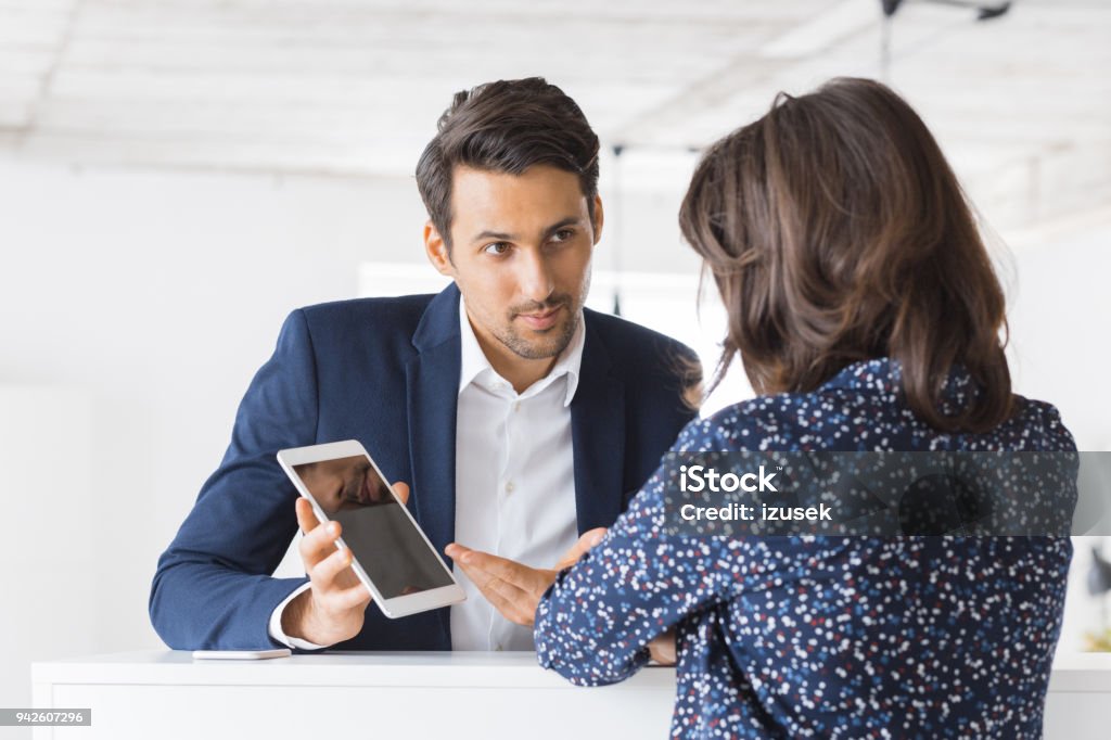 Business colleagues working together in office Businessman showing a proposal on digital tablet to female colleague. Two business people working together at office using digital tablet. Digital Tablet Stock Photo