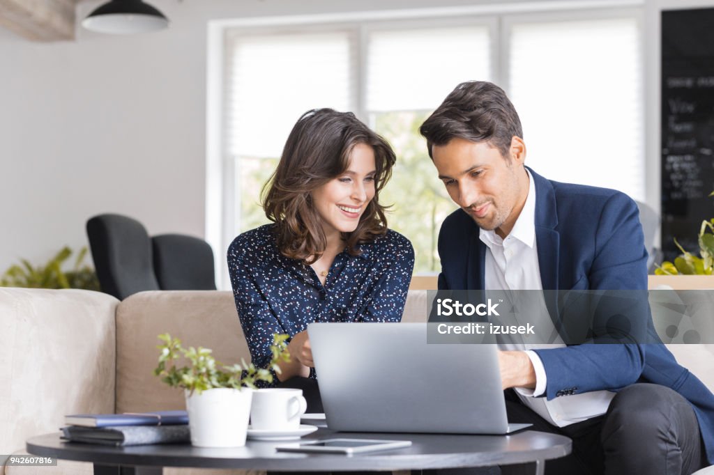 Modern business people working at a cafe Two business colleagues sitting in a cafe and working on laptop. Business couple having a meeting in cafe. Financial Advisor Stock Photo