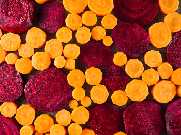 istock Beetroot and carrot slices over dark gray marble background. 942607904