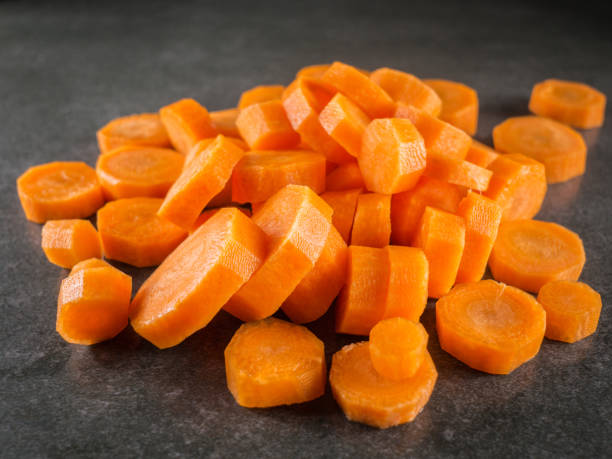 куча моркови ломтик на темно-серый мраморный фон. - carotene healthy eating macro close up стоковые фото и изображения