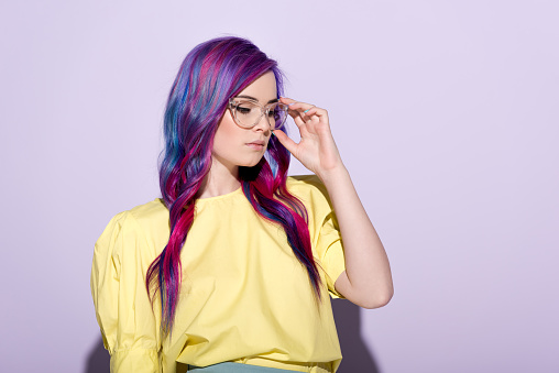 sensual young woman with colorful hair and stylish eyeglasses on pink