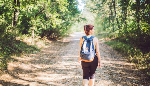 istock Backpacker woman walking into the forest. 942608660