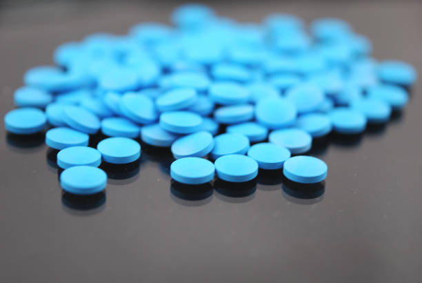 istock Blue round tablets close-up on black background 942615928