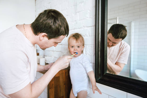 istock Man brushing teeth of adorable baby 942619368