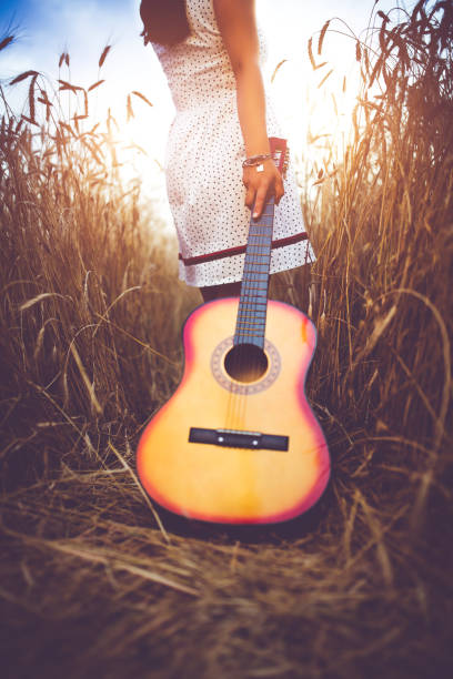 istock Woman with a guitar walking  through a high grass. 942619786