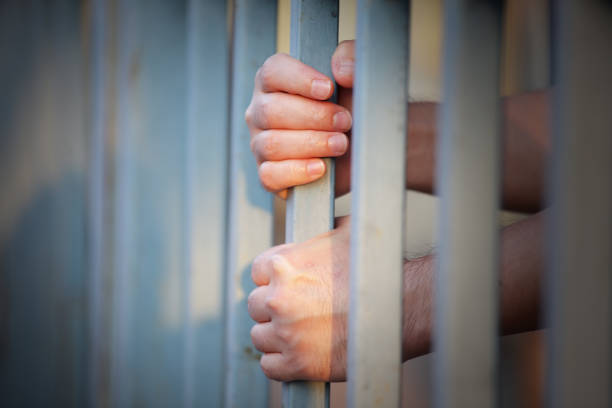istock hands of prisoner in jail as background. 942622150