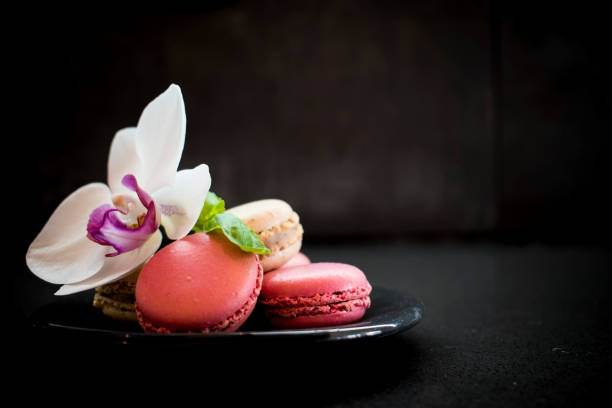 istock Tender pink and cream macarons on dark stone background. 942622226