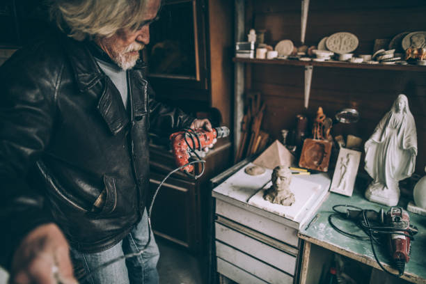 istock Senior man grinding his art work in the garage 942622548