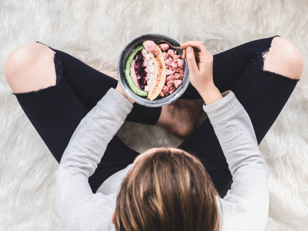 Berry smoothie and muesli with banana Berry smoothie and muesli with banana, coconut, meringue and jam on a blue plate, which is held by a young woman in her hands eating chia seeds stock pictures, royalty-free photos & images
