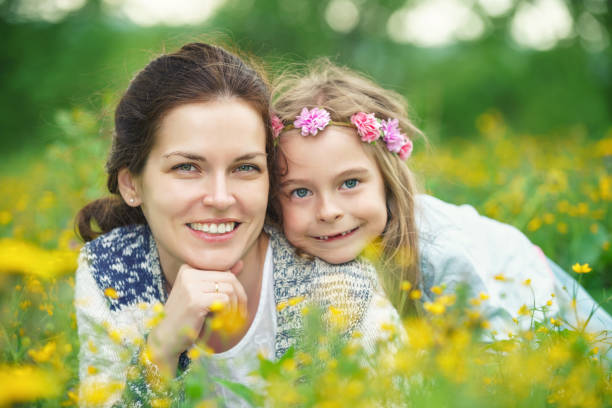 istock Mother and daughter on spring meadow with blooming flowers 942627328