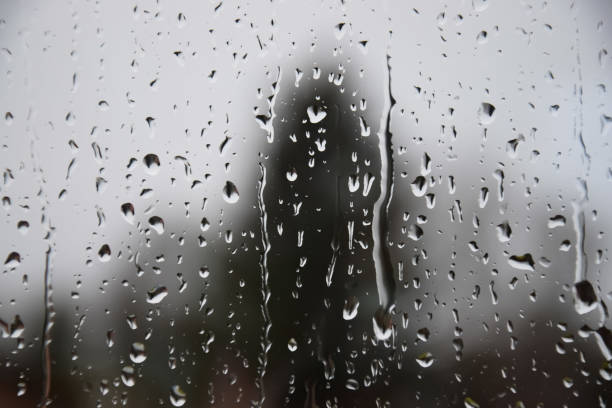 Sad and depressive mood on a cold day, water drops running down a glass surface like tears, dark colors