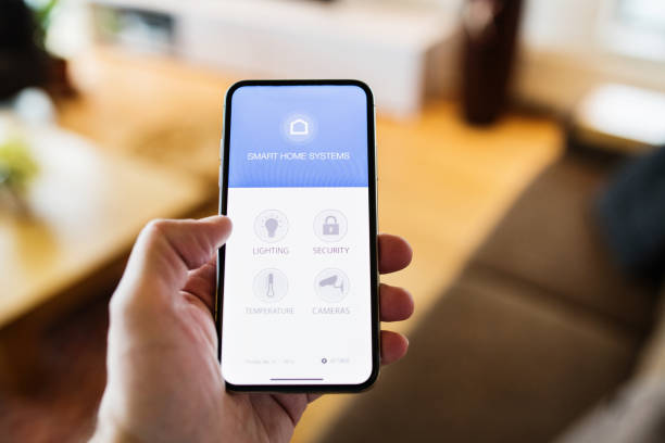 istock A woman holding a smartphone with smart home screen. 942631026