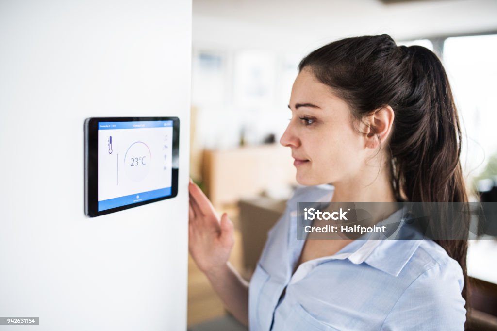 A woman looking at tablet with smart home screen. A woman looking at tablet with smart home control system. Thermostat Stock Photo