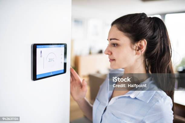 A Woman Looking At Tablet With Smart Home Screen Stock Photo - Download Image Now - Thermostat, Women, Intelligence