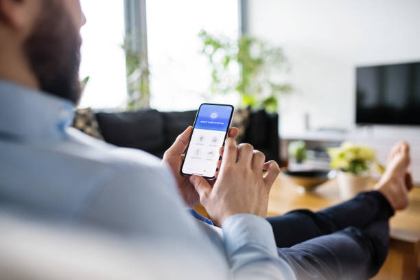 um homem segurando um smartphone com tela de casa inteligente. - computer monitor symbol isolated photograph - fotografias e filmes do acervo