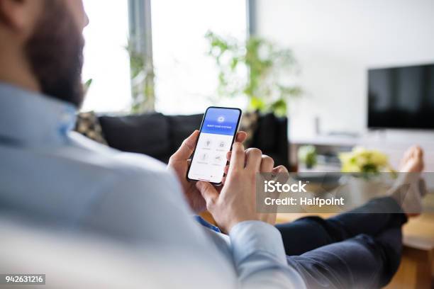 Foto de Um Homem Segurando Um Smartphone Com Tela De Casa Inteligente e mais fotos de stock de Automação residencial