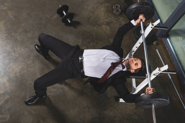 biznesmen w garniturze szkolenia ze sztangą w centrum sportowym - businessman exercising training muscular build zdjęcia i obrazy z banku zdjęć