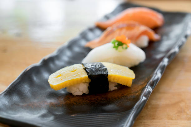 zbliżenie kuchni japońskiej nigiri sushi ustawione na czarnym talerzu serwowane w japońskiej restauracji spożywczej. - main course salmon meal course zdjęcia i obrazy z banku zdjęć