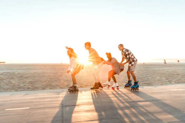 friends roller skating on the boardwalk in venice beach - santa monica promenade - los angeles, usa - santa monica venice beach california santa monica beach imagens e fotografias de stock