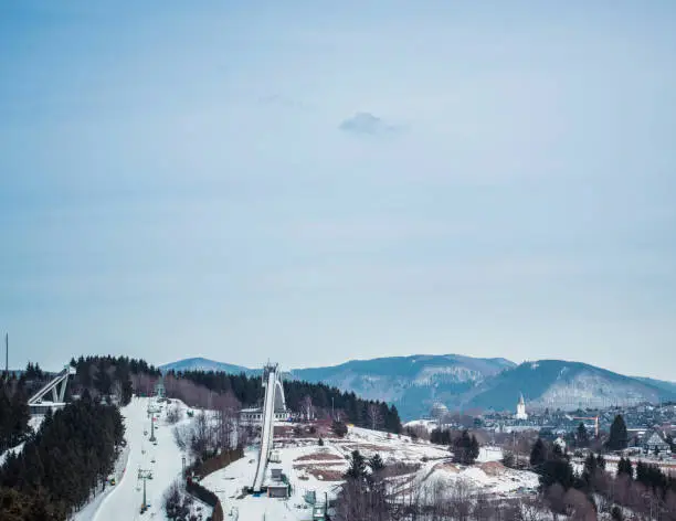 Mountain wintersport scenery with ski-jump under blue cloudy sky. Winterberg, Germany.