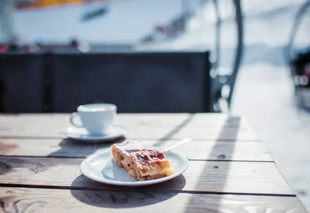 Pastries on white plate on wooden outdoor table in wintersport area.