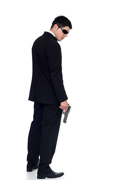 agent secret au costume noir tenant arme à feu isolé sur blanc - gun men spy suit photos et images de collection