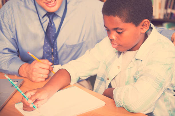 istock Teacher, mentor helps elementary-age schoolboy with homework. 942654470