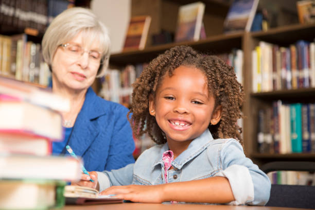 istock Teacher, mentor helps elementary-age schoolgirl with homework. 942654640