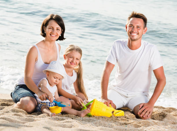 istock Parents with two kids playing with toys on beach 942659046