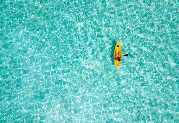 Woman in a canoe over turquoise, tropical waters in the Maldives