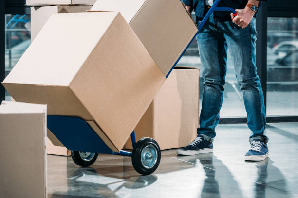 Close-up view of delivery man carrying boxes on cart stock photo