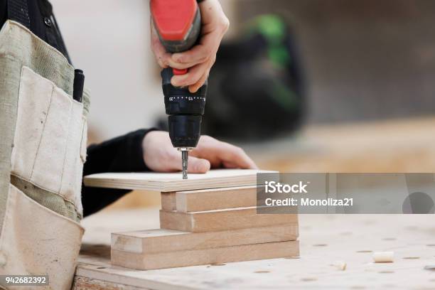 Carpenter Working With An Electric Screwdriver On The Work Bench Close Up Focus On The Tool Stock Photo - Download Image Now