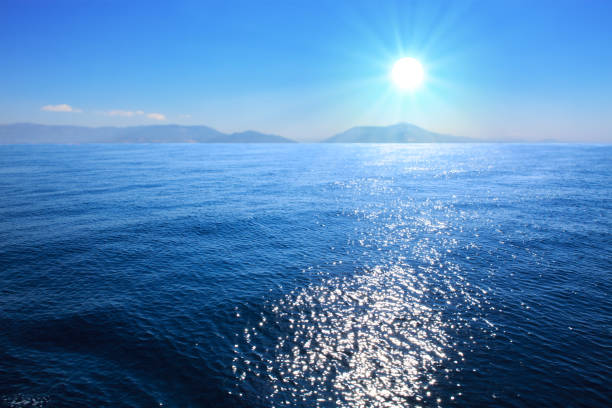 Summer landscape with sea and mountains silhouettes and sunrise.