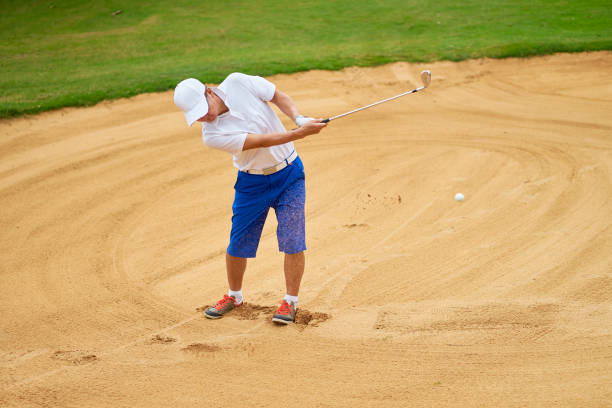 istock Asian player swinging club in bunker of a course 942685548