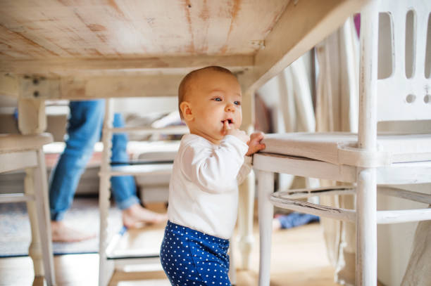 A baby girl under the table at home.