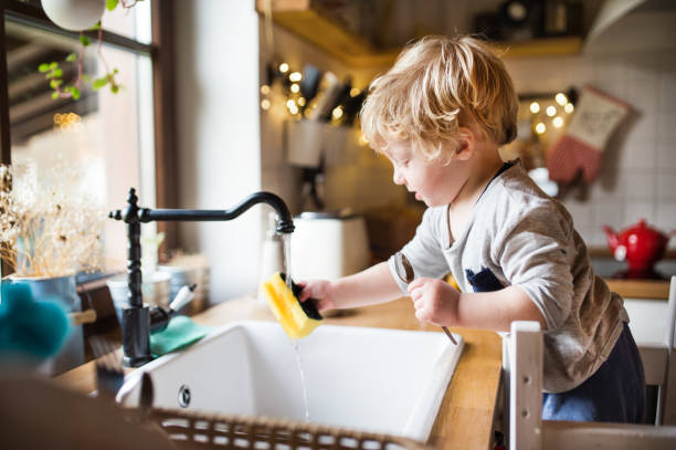 A toddler boy washing up the dishes. A cute toddler boy washing up the dishes. washing dishes stock pictures, royalty-free photos & images